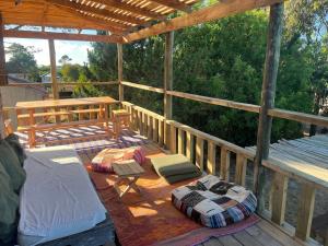 een houten terras met kussens, een tafel en een bank bij Castillito de la viuda casa para 5o 6 personas in Punta Del Diablo