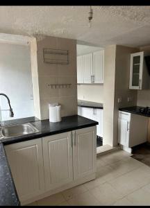 eine Küche mit weißen Schränken und einer Spüle in der Unterkunft Cozy & Comfy Apartments Dundee in Dundee