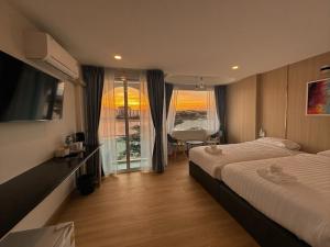 a hotel room with two beds and a window at โรงแรมดีวิว โกลเด้นไทรแองเกิ้ล เชียงแสน - Dview Golden Triangle Hotel Chiangsaen in Golden Triangle