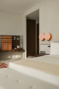 een witte slaapkamer met 2 bedden en een spiegel bij SLS The Red Sea in Ḩanak