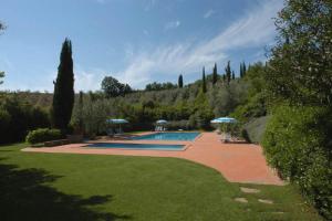 a swimming pool with umbrellas in a garden at Comiti Farmhouse Apt Bondone in Montaione
