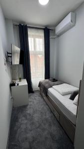 um pequeno quarto com uma cama e uma janela em Libero apartmani em Zaječar