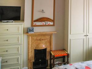 a room with a fireplace with a chair and a mirror at Heath View Cottage in Westleton
