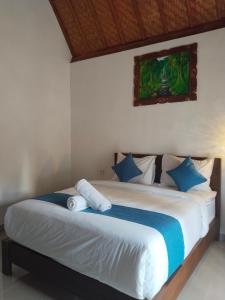 ein Schlafzimmer mit einem großen Bett mit blauen und weißen Kissen in der Unterkunft Santhi Laba Bungalow in Nusa Penida