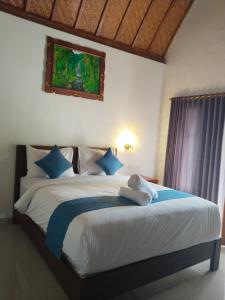ein Schlafzimmer mit einem großen weißen Bett mit blauen Kissen in der Unterkunft Santhi Laba Bungalow in Nusa Penida