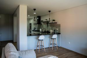 a living room with a kitchen and two stools at Casa da Boucinha in Celorico de Basto