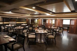 a restaurant with tables and chairs in a room at Cygnett Inn Ramachandra in Kurmannapalem
