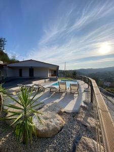 a house with a swimming pool and two chairs at Casa da Boucinha in Celorico de Basto