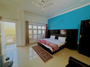 een slaapkamer met een bed en een blauwe muur bij Hotel Vasundhara Palace, Chamba in Chamba