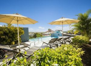 a patio with chairs and umbrellas and a swimming pool at VillasRoyale Diamante - A Diamond to Discover! in Meloneras