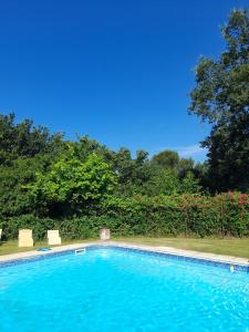 een groot zwembad met 2 stoelen en bomen bij Maison d'hôte - Le Valdaine in Portes-en-Valdaine