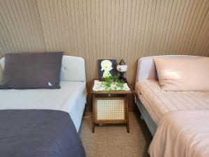 a room with two beds and a night stand with a table with a bed istg at Hanok Story in Jeonju