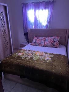 a bed in a bedroom with a window and a bedspread at Cozy Townhouse with a Backyard in Sheikh Zayed