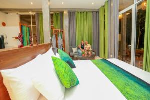 a bedroom with a bed and two people sitting in a chair at Villa Sanni 18 in Hikkaduwa