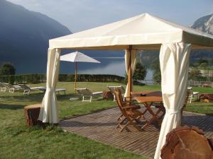 une tente blanche avec une table et des chaises sur une terrasse dans l'établissement Lake&Nature Hotel Gloria, à Molveno