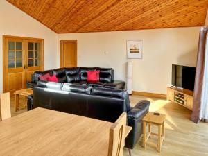 een woonkamer met een zwarte leren bank en een televisie bij Fois Bhrus in White Bridge