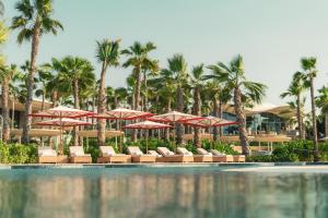 een zwembad met stoelen, parasols en palmbomen bij SLS The Red Sea in Ḩanak