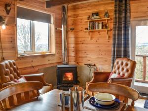 un soggiorno con un tavolo e una stufa a legna di Glenkens Lodge a Dalry