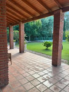 eine Ziegelterrasse mit einer Holzpergola und ein Park in der Unterkunft Rincón del roble in Veinticinco de Mayo + 2 Fotos