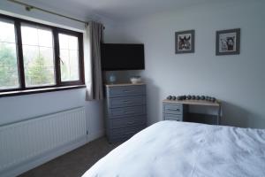 a bedroom with a bed and a tv and window at Carreg Llwyd in Caerphilly