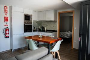 a kitchen with a wooden table and white cabinets at Recanto da Boucinha - T2 in Veade