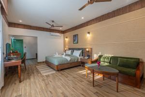 een slaapkamer met een bed, een bank en een tafel bij TRIDEUS THE WILD FRASER Corbett in Rāmnagar