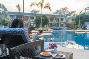 een vrouw met een glas wijn naast een zwembad bij TRIDEUS THE WILD FRASER Corbett in Rāmnagar
