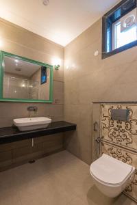 een badkamer met een toilet, een wastafel en een spiegel bij TRIDEUS THE WILD FRASER Corbett in Rāmnagar