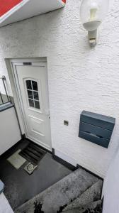 a white building with a door and a step leading to it at Souterrain Casa Siegburg in Siegburg