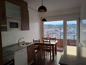 una cocina con mesa y sillas y una ventana en Torre Plaza 5, en Boiro