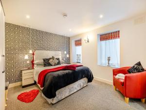 een slaapkamer met een bed en een rode stoel bij Ty Llyn Cottage in Brynteg +16 foto's
