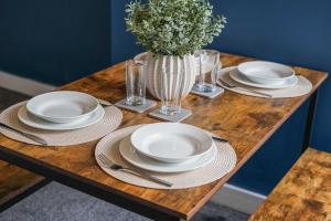 una mesa de madera con platos y un jarrón de flores en Cosy Home in Grimsby Town Centre, en Grimsby