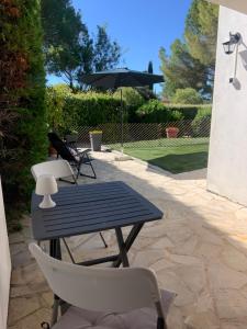 a patio with a table and chairs and an umbrella at Studio indépendant avec terrasse et jardin au calme chez Pascale in Saint-Clément-de-Rivière