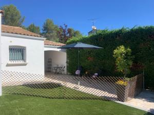 une clôture avec un parasol dans une cour dans l'établissement Studio indépendant chez Pascale, à Saint-Clément-de-Rivière