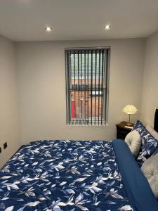 een slaapkamer met een blauw bed en een raam bij Marble Black Deluxe in Gloucestershire