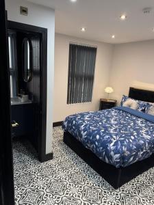 een slaapkamer met een blauw bed en een spiegel bij Marble Black Deluxe in Gloucestershire