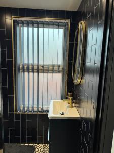 een kleine badkamer met een wastafel en een spiegel bij Marble Black Deluxe in Gloucestershire