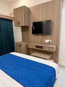 een slaapkamer met een bed met een blauwe deken en een televisie bij Hotel Beral in Ahmedabad