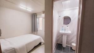 a white bathroom with a bed and a sink at 1971 Sinpung Inn in Seoul