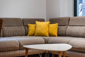a brown couch with yellow pillows and a coffee table at Pine & Sea Retreat in Golem +22 photos