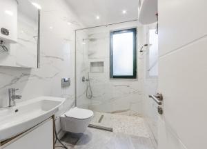 ein weißes Badezimmer mit Toilette und Waschbecken in der Unterkunft Pine & Sea Retreat in Golem + 22 Fotos