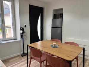 een keuken met een houten tafel met stoelen en een koelkast bij Maison avec courette in Courlay +2 foto's