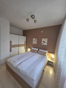 een slaapkamer met een groot bed met witte lakens bij APart Residence Shumen in Shumen