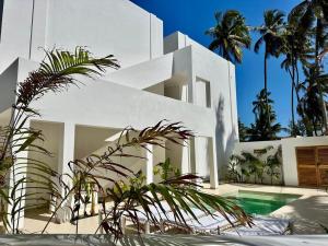 een wit huis met een zwembad en palmbomen bij Two Bedroom Beach Front Apartment with pool in Kiwengwa