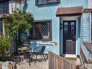 una casa blu con tavolo, sedie e porta di Turning Tides Cottage a Scratby
