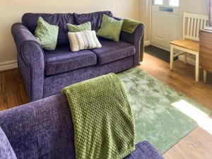 un divano viola con cuscini in soggiorno di Turning Tides Cottage a Scratby