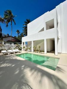 een wit huis met een zwembad ervoor bij Two Bedroom Beach Front Apartment with pool in Kiwengwa