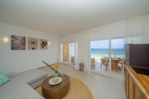 een woonkamer met een bank, een televisie en een tafel bij Two Bedroom Beach Front Apartment with pool in Kiwengwa