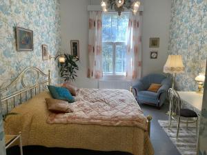 a bedroom with a bed and a chair and a window at Old Hospital & Sauna at the Beach in Pargas