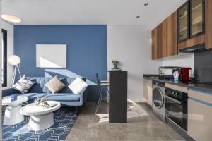 a living room with a blue couch and a kitchen at Bright Modern Studio, Gauthier in Casablanca